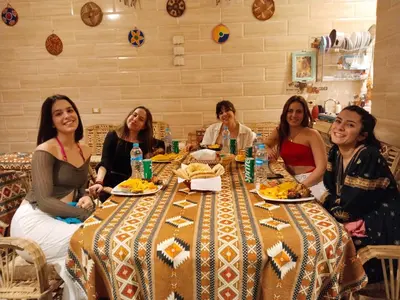 a group of women sitting around a table with food at Bakar House in Aswan