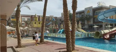 a woman standing next to a pool at a resort at Mirage Aqua Resort 2 Bedroom Apartment in Hurghada