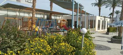 a playground in front of a building with yellow flowers at Mirage Aqua Resort 2 Bedroom Apartment in Hurghada