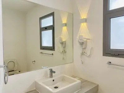 a white bathroom with a sink and a mirror at Ground Spacious 1-BR Apt @ SwanLake El Gouna ! in Hurghada