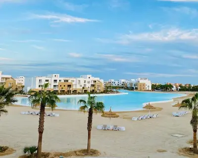 a view of a beach with chairs and umbrellas at Rustic 1 BR-Apt@ Swanlake El Gouna ! in Hurghada