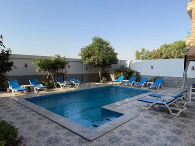 a swimming pool with lounge chairs next to a building at Panorama Hotel in Luxor