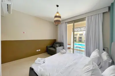 a bedroom with a bed and a chair and a window at Smooth & Snug 1 BDR Mangroovy Free Beach & Pool Access in Hurghada