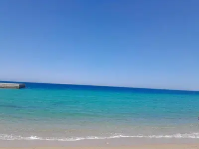 a beach with the ocean and a pier at Cozy beachfront apartment in Al Ahyaa suitable for a family with children in Hurghada