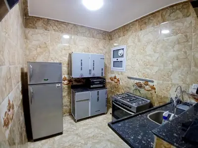a small kitchen with a refrigerator and a stove at Sky Guest House in Luxor