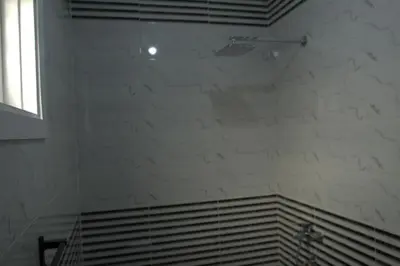 a bathroom with a white tile wall and a shower at Mogran Guest House in Luxor