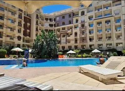 a swimming pool in front of a large building at Sunny studio with 3 swimming pools Florenza Hurghada in Hurghada