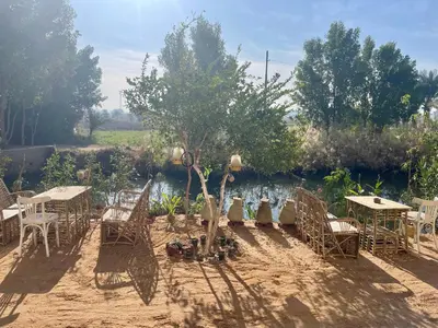a group of tables and chairs in front of a river at Karima House in Luxor