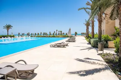 a swimming pool with chaise lounge chairs and palm trees at Cozy 1 Bedroom Ground Floor Apartment with Pool in Hurghada