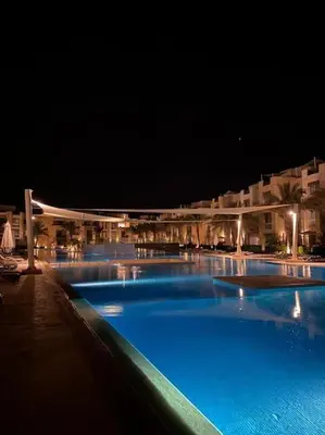 a large swimming pool with blue water at night at Cozy 1 Bedroom Ground Floor Apartment with Pool in Hurghada