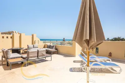 a patio with a beach chair and an umbrella at 2-BR Penthouse with roof terrace in Abu Tig Marina in Hurghada
