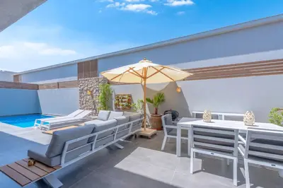 a patio with a table and chairs and an umbrella at Tropical 2BR Paradise in Bali, El Gouna. Pool, Patio & BBQ in Hurghada