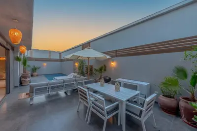 a patio with a table and chairs and a couch at Tropical 2BR Paradise in Bali, El Gouna. Pool, Patio & BBQ in Hurghada
