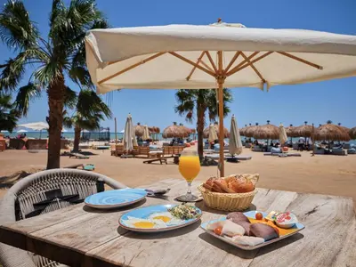a wooden table with food and a drink on a beach at Boutique Residence Mangroovy-Lemon Spaces Gouna in Hurghada
