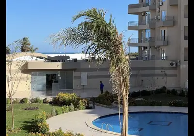 a palm tree in front of a building with a swimming pool at Princess resort in Hurghada