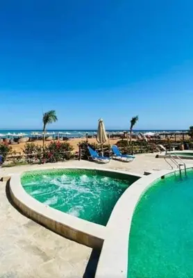 a swimming pool with a beach in the background at Turtle beach apartment in Hurghada