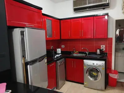 a kitchen with red cabinets and a washing machine at Turtle beach apartment in Hurghada