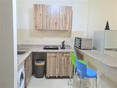 a kitchen with wooden cabinets and a counter with blue chairs at 2 bedroom modern flat at Makadi heights in Hurghada