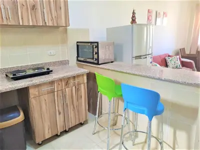 a kitchen with a counter with two chairs and a microwave at 2 bedroom modern flat at Makadi heights in Hurghada