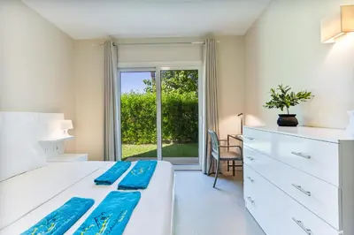 a bedroom with a white bed and a sliding glass door at Cheerful space with a huge garden and pool in Hurghada