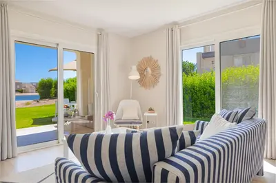 a living room with striped couches and a sliding glass door at Cheerful space with a huge garden and pool in Hurghada