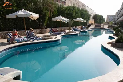 a swimming pool with people sitting on chairs and umbrellas at FOX SAHEL AQUA RESORT ELGOUNa& Kite in Hurghada