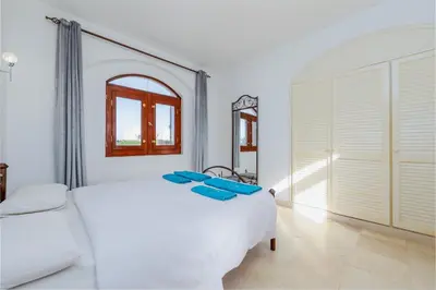 a white bedroom with a bed and a mirror at 3-Bedroom Apartment - Great location- Upper Nubia in Hurghada