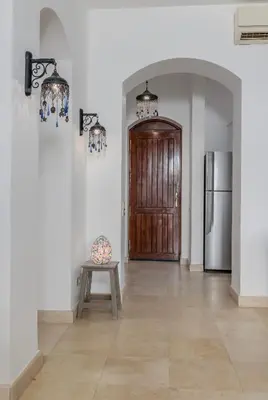 a hallway with a wooden door and a table and a refrigerator at 3-Bedroom Apartment - Great location- Upper Nubia in Hurghada