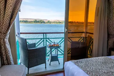 a room with a balcony with a view of the water at Sonesta Moon Goddess Cruise Ship From Luxor to Aswan - 04 & 07 nights Every Monday in Luxor