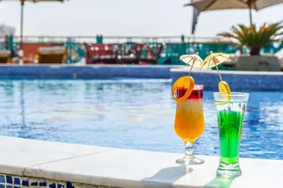 two drinks sitting on a table next to a swimming pool at Sonesta Moon Goddess Cruise Ship From Luxor to Aswan - 04 & 07 nights Every Monday in Luxor