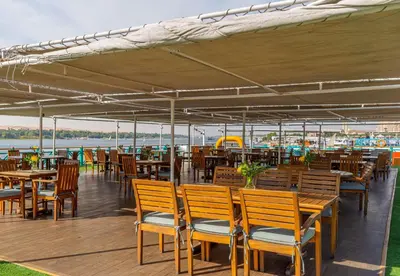 a restaurant with wooden tables and chairs on a deck at Sonesta Moon Goddess Cruise Ship From Luxor to Aswan - 04 & 07 nights Every Monday in Luxor