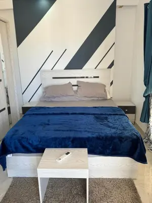 a bedroom with a bed with a blue blanket and a table at Inter Prime apartment 3 in Hurghada