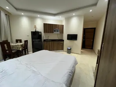 a bedroom with a white bed and a kitchen with a table at La Quinta Beach Resort in Hurghada