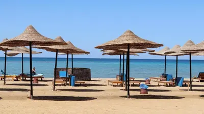 a beach with chairs and umbrellas on the sand at La Quinta Beach Resort in Hurghada