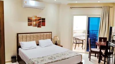 a bedroom with a bed and a desk and a balcony at La Quinta Beach Resort in Hurghada