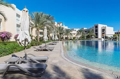 a pool at a resort with lounge chairs and umbrellas at Cozy 1BR Apartment in Mangroovy with pool in Hurghada