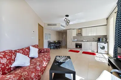 a living room with a red couch and a kitchen at Cozy 1BR Apartment in Mangroovy with pool in Hurghada