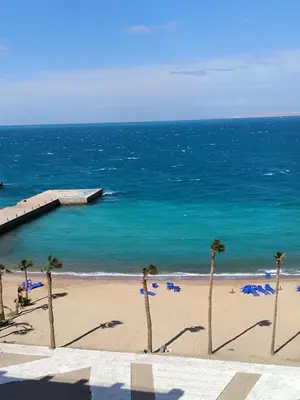 a beach with chairs and palm trees and the ocean at Juliana beach studio front of the beach in Hurghada