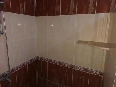 a bathroom with a shower with brown and white tile at Obelisk house in Jazīrat al ‘Awwāmīyah