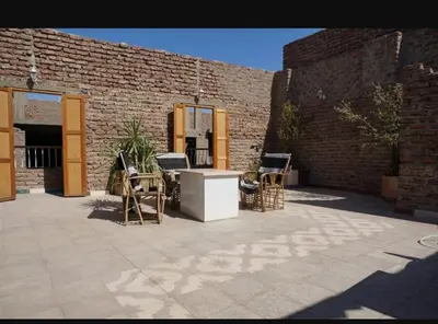 a patio with chairs and a table and a brick wall at Obelisk house in Jazīrat al ‘Awwāmīyah