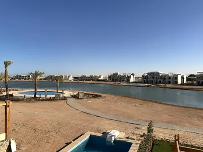 a swimming pool next to a river with buildings at Charming 3BR Villa/Free Pool & Lagoon Access@Gouna in Hurghada
