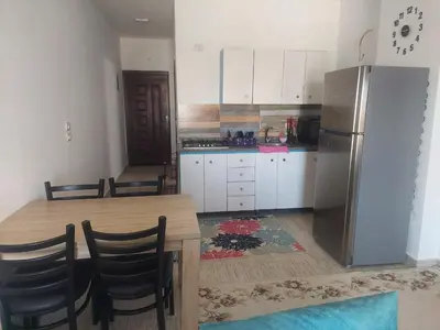 a kitchen with a wooden table and a refrigerator at Makramia 2 bedroom apartment in Hurghada
