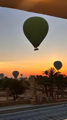 a green hot air balloon flying over a cemetery at Amenhotep Apartments in Luxor