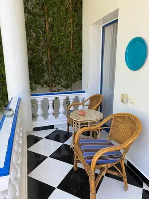 a patio with chairs and a table on a checkered floor at Villa Kaslan Apartments in Luxor