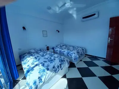 two beds in a room with a blue light at Villa Kaslan Apartments in Luxor