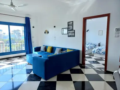 a living room with a blue couch and a bedroom at Villa Kaslan Apartments in Luxor