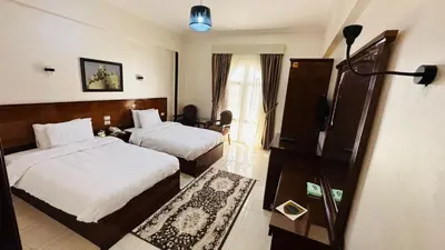 a hotel room with two beds and a television at Badr Hotel & Resort El Kharga in Kharga