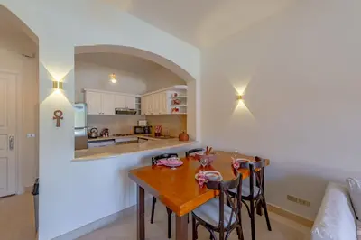 a kitchen and dining room with a wooden table and chairs at Stunning poolhouse duplex - 3 bedrooms - South Marina - El Gouna in Hurghada