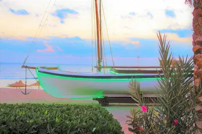 a boat sitting on the beach next to the ocean at Rohanou Beach Resort in Quseir