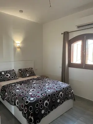 a bedroom with a bed with a black comforter and a window at Villa Muhammad in Quseir